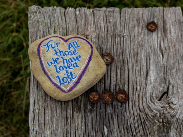 photo of a painted stone with the following written in blue letters "for those who've loved and loss" to illustrate the power of writing about grief.