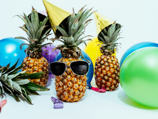 Photo of a pineapple with sunglasses surrounded by other pinapples and balloons to illustrate teh prizes you can win as you D.E.P.A.R.T. 2024